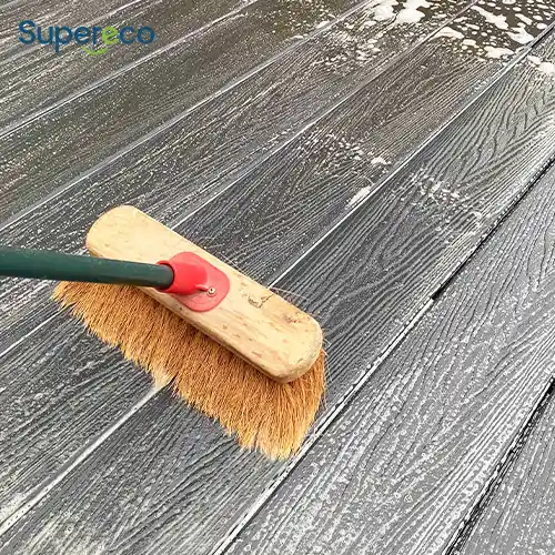 contractor cleaning wpc decking boards with soft brush and hose on commercial project site 1