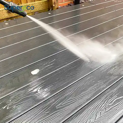 contractor cleaning wpc decking boards with soft brush and hose on commercial project site 2